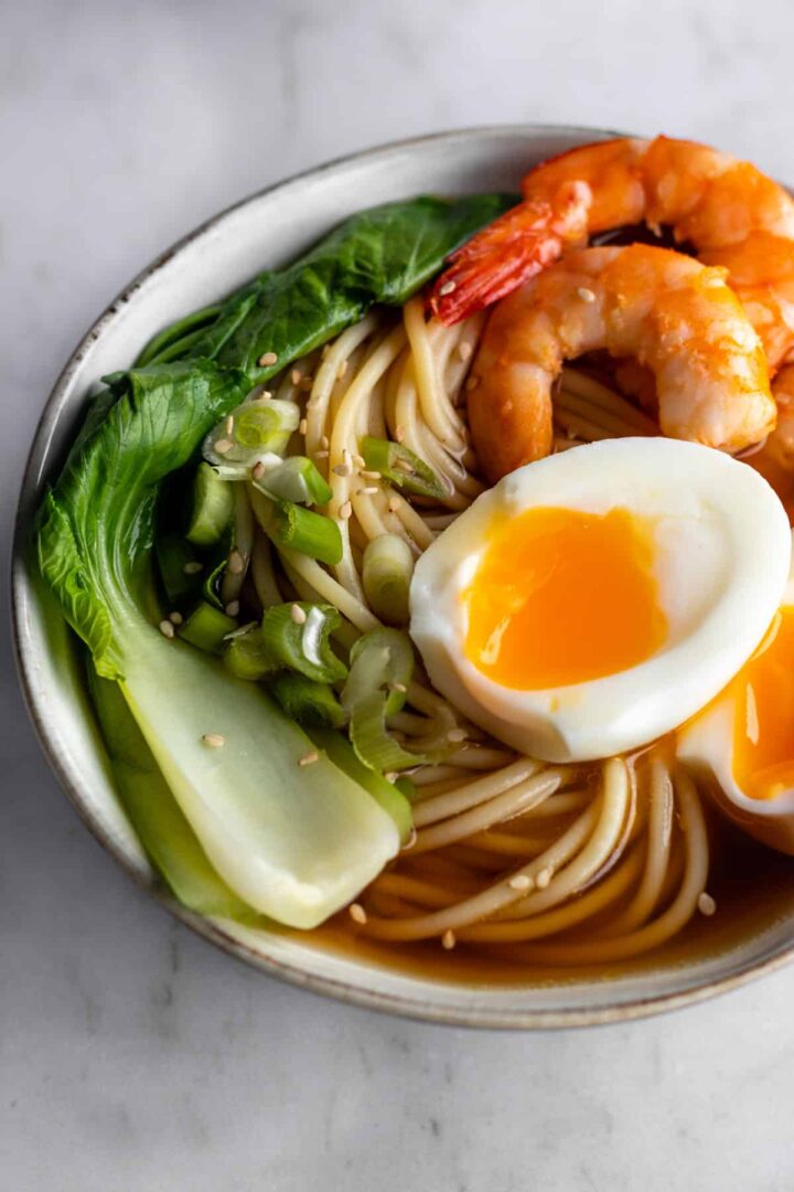 close-up ramen bowl with noodles, shrimp, boiled egg, green onions and bok choy