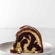 a small plate with one slice of marble cake with chocolate cream on top