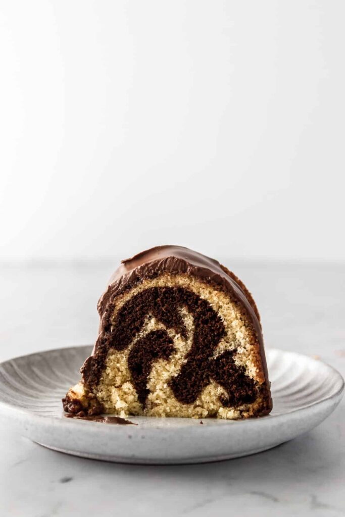 a small plate with one slice of marble cake with chocolate cream on top