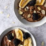 two chocolate quinoa bowls with banana, blackberries and flaked almonds