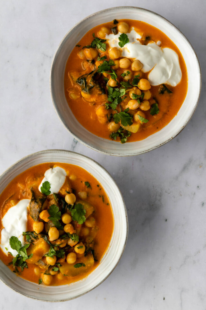 two bowls with chickpea curry, coconut yogurt and chopped coriander