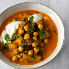 a bowl with vegetable curry, yogurt and chopped coriander