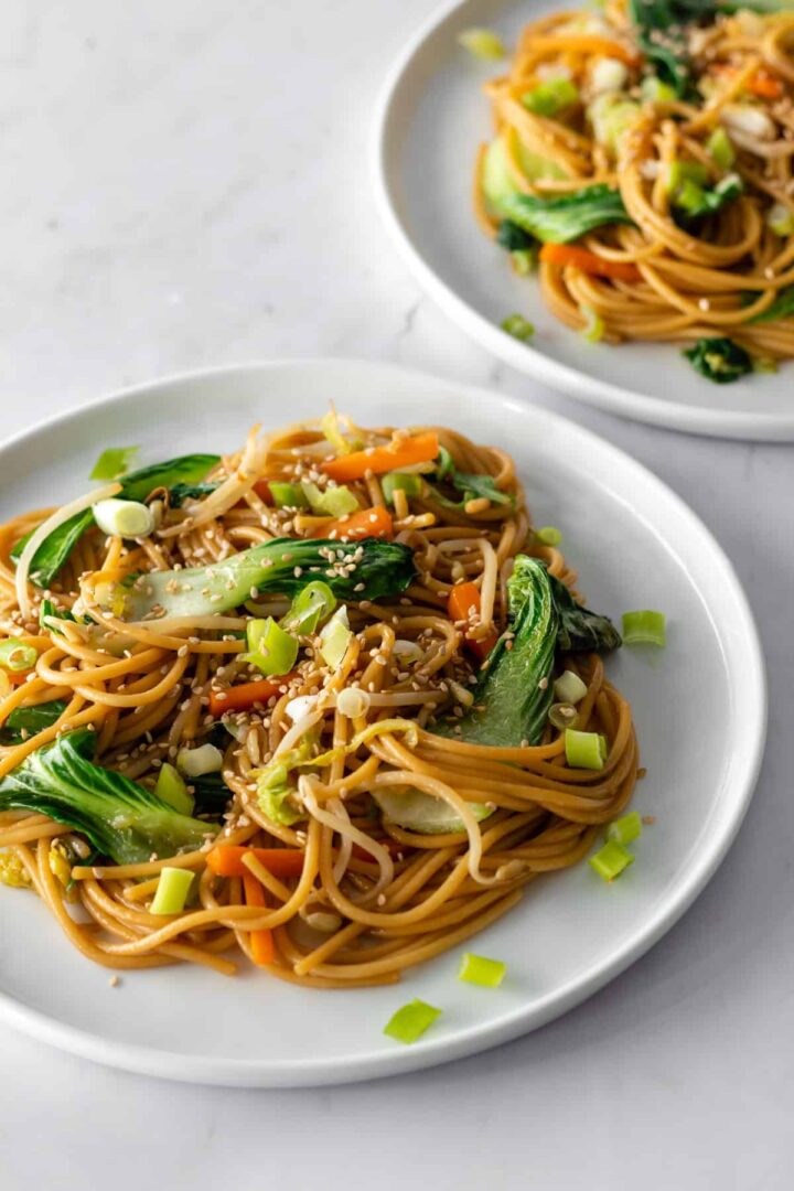 Vegetable lo mein served on two white plates