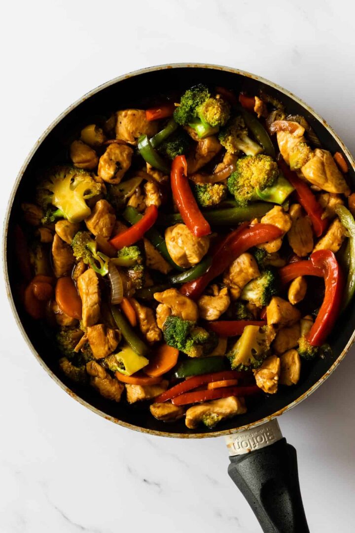 a pan with chicken, broccoli, bell peppers, onion, and sliced carrots