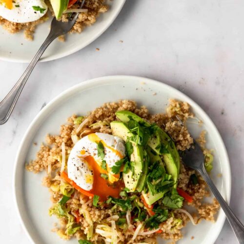 two plates served with quinoa mixed with vegetables, poached egg, sliced avocado and chopped coriander on top