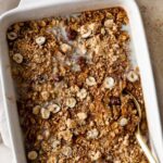 pumpkin baked oatmeal on a baking dish with a gold spoon on the side