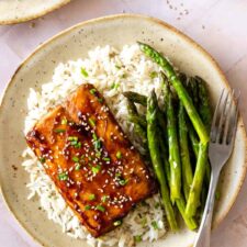 a plate with salmon, white rice, asparagus, sesame seeds and chopped chives