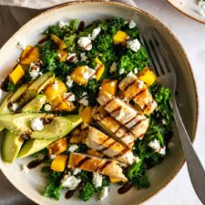 a plate with kale, chicken, avocado, crumbled feta and balsamic glaze