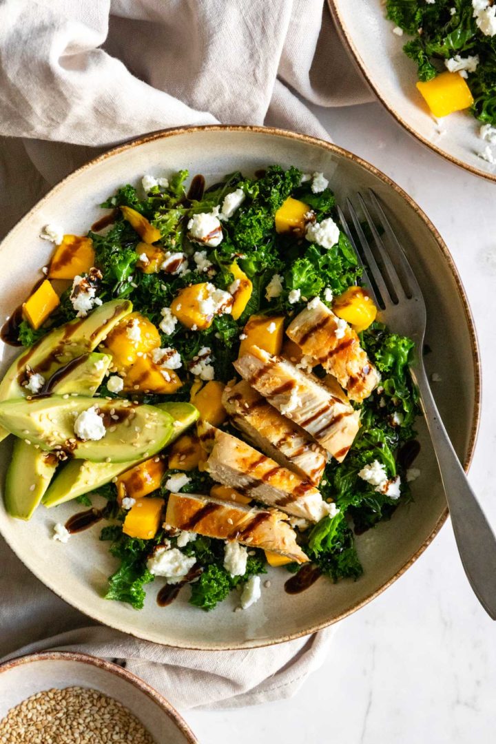 a plate with kale, chicken, avocado, crumbled feta and balsamic glaze