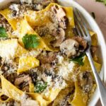 a plate served with mushroom pappardelle topped with coriander and grated parmesan