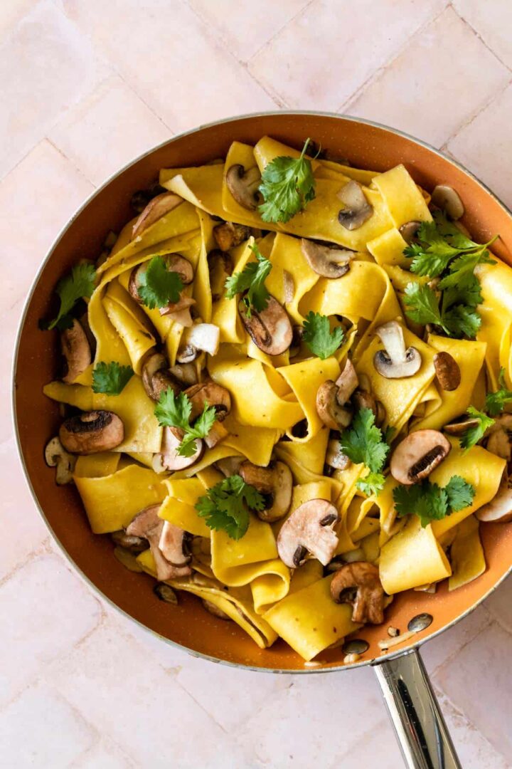 pasta wish mushrooms, garnished with coriander inside a pan.