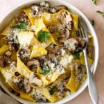 a plate served with mushroom pappardelle with grated parmesan on top and coriander