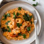 shrimp risotto with fresh coriander on a plate with a fork on the side