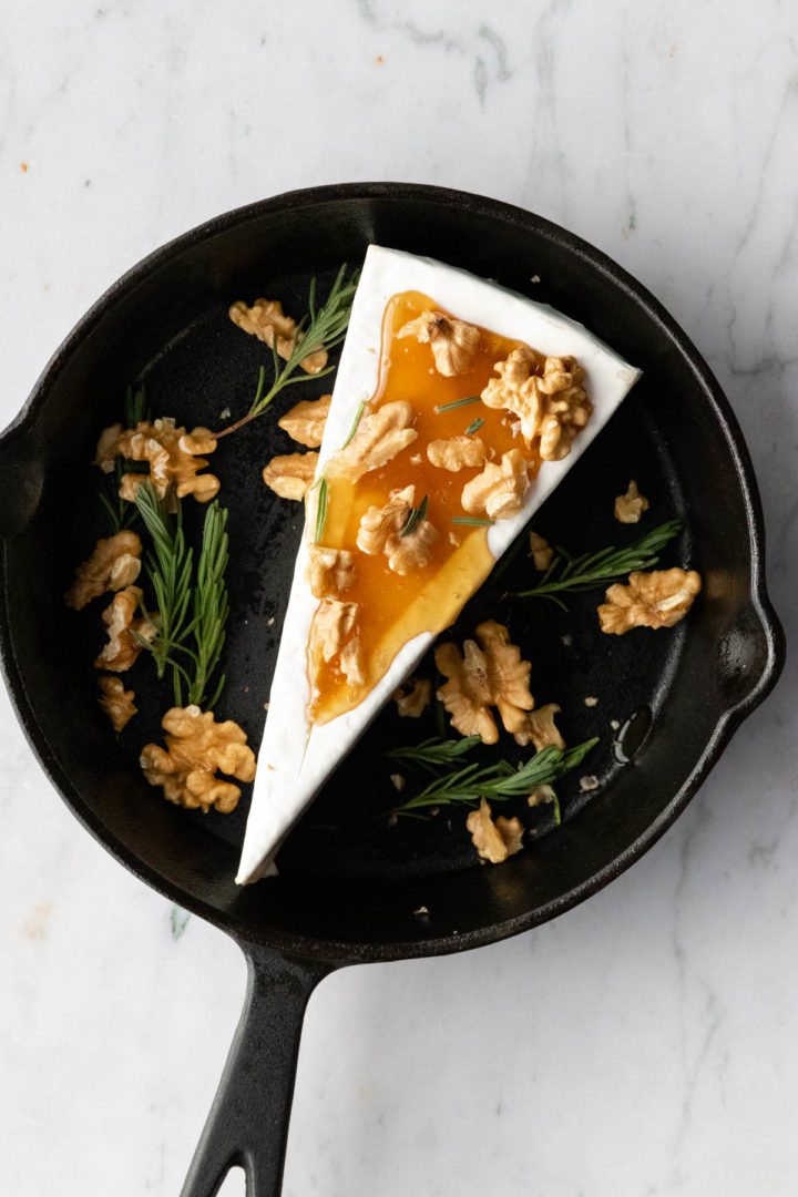 a skillet with brie, honey, rosemary and walnuts before going to the oven