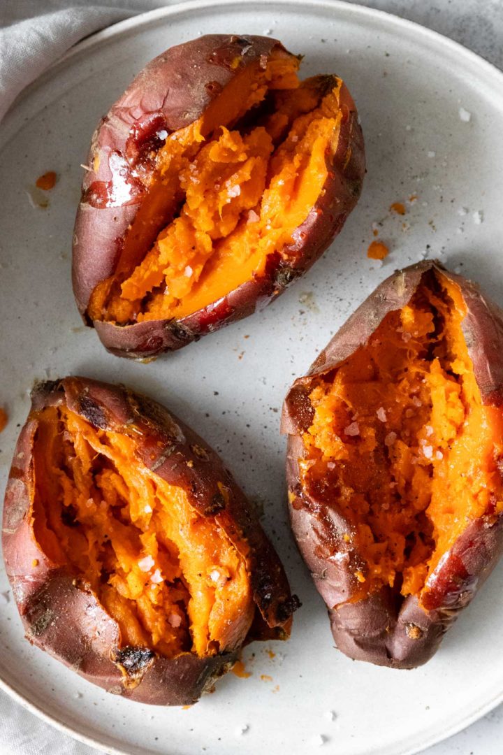 close-up of three sweet potatoes on a plate seasoned with salt and black pepper