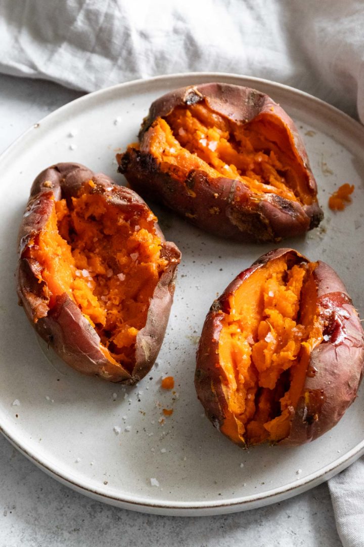 orange sweet potatoes on a plate seasoned with salt and black pepper