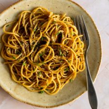 one plate served with noodles topped with sesame seeds and chopped chives