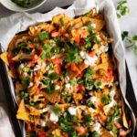 a baking tray with sheet pan nachos topped with coriander