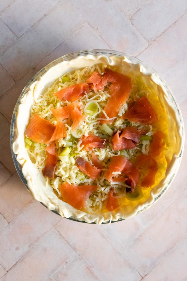 smoked salmon, leek, and mozzarella cheese on top of the quiche crust inside a baking dish