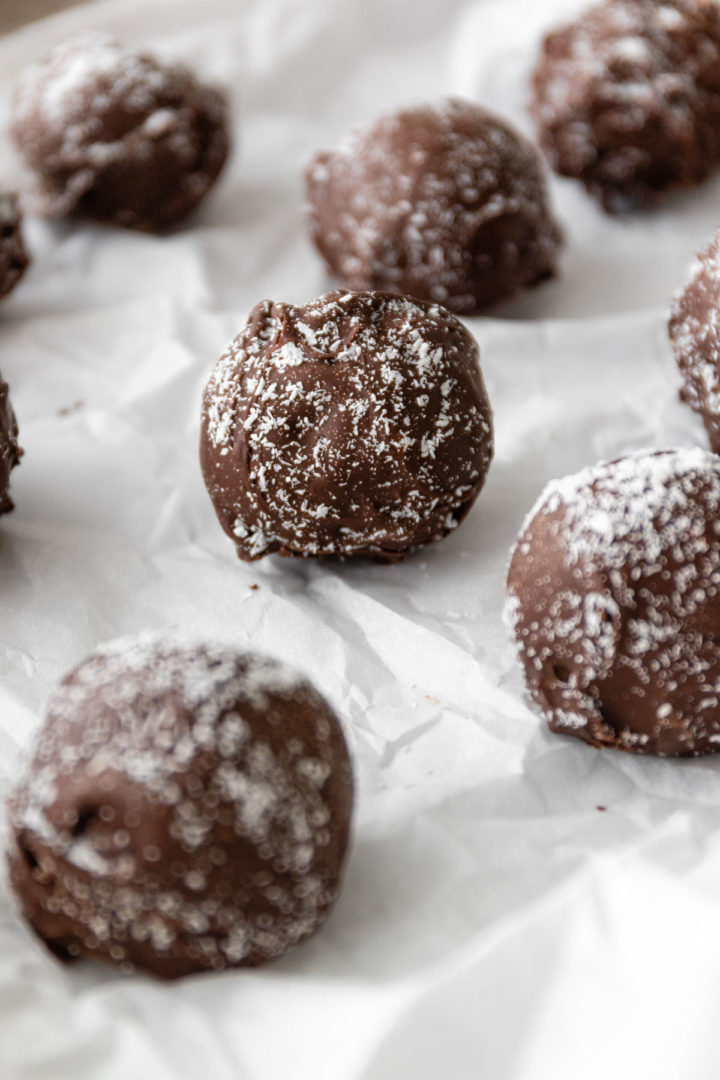 close up of chocolate coconut balls on top of parchment paper