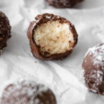 close up of a chocolate coconut ball with one bite