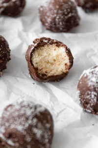 close up of a chocolate coconut ball with one bite