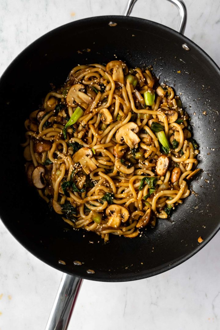 Yaki Udon noodles inside a wok and garnished with sesame seeds