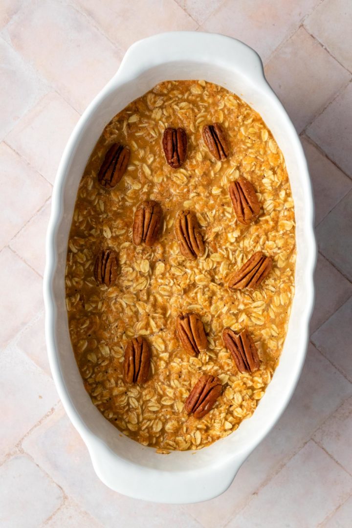 a baking dish with oats, carrots and pecan nuts on top before going to the oven