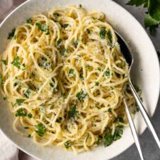 a bowl with lemon pasta, a fork and a spoon.