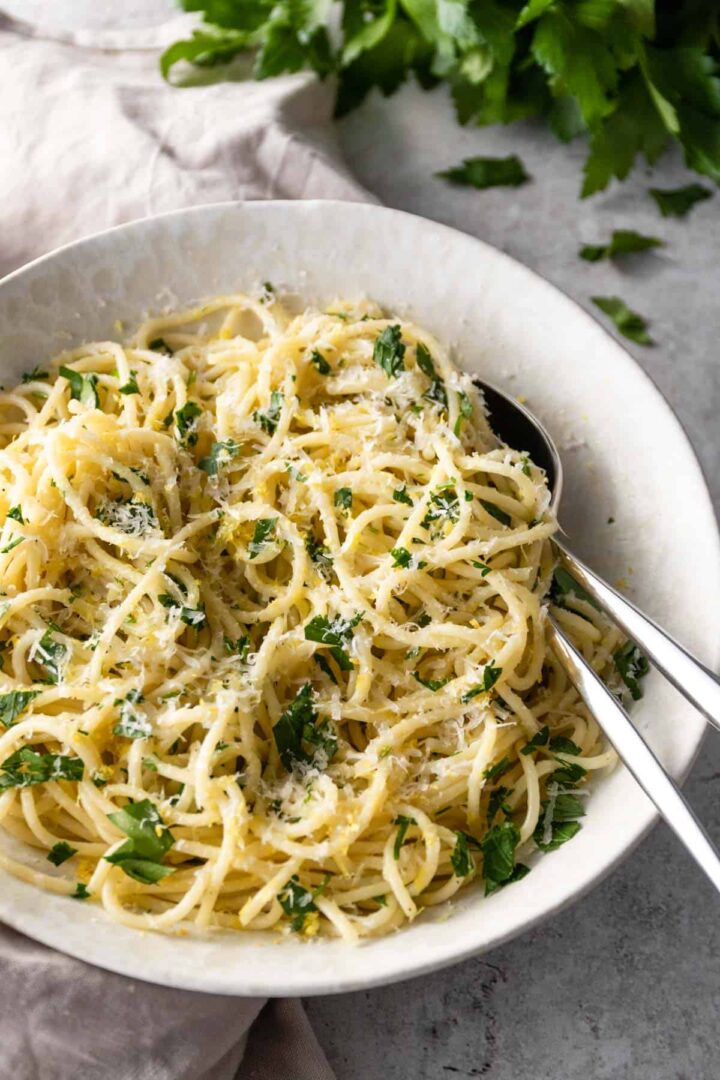 a bowl with lemon pasta with lemon zest, chopped parsley and grated parmesan on top