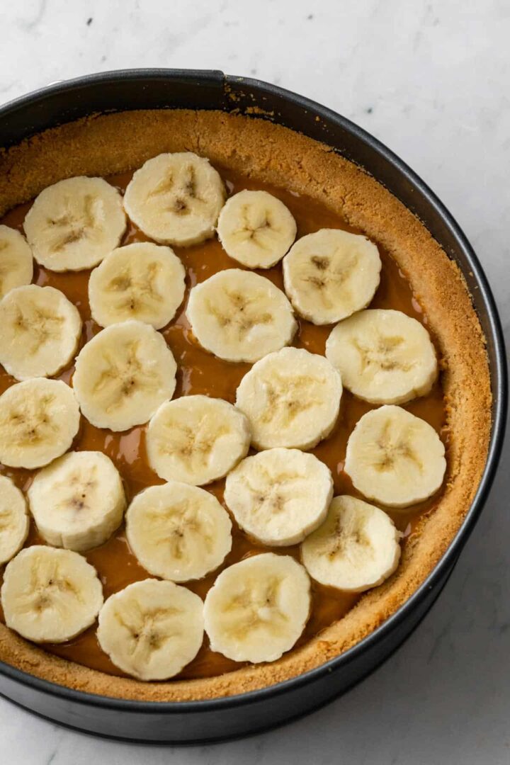 inside look of a banoffee pie with a biscuit layer, followed by a dulce de leche layer and a layer of sliced bananas