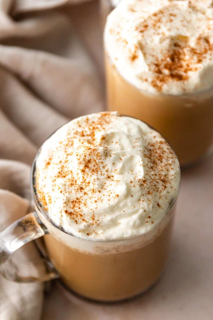 two mugs served with pumpkin spice latte with whipped cream and cinnamon