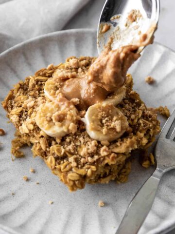 banana oatmeal served on a plate with peanut butter and with a fork on the side