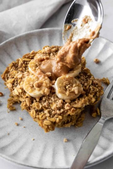banana oatmeal served on a plate with peanut butter and with a fork on the side