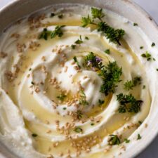 whipped feta dip served on a bowl with honey, sesame seeds, and fresh thyme on top