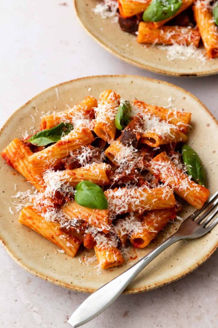 one plate served with pasta, eggplant, tomato sauce, parmesan cheese and basil