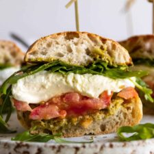 one Caprese sandwich with arugula, mozzarella, tomato and pesto