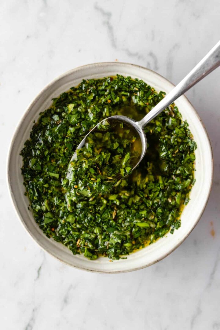 a small bowl with chimichurri sauce and a spoon