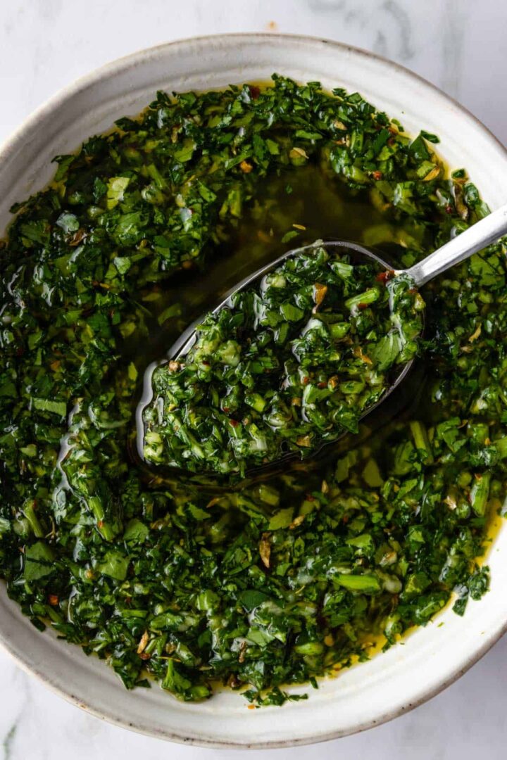 close up of a small bowl with a spoon and chimichurri sauce