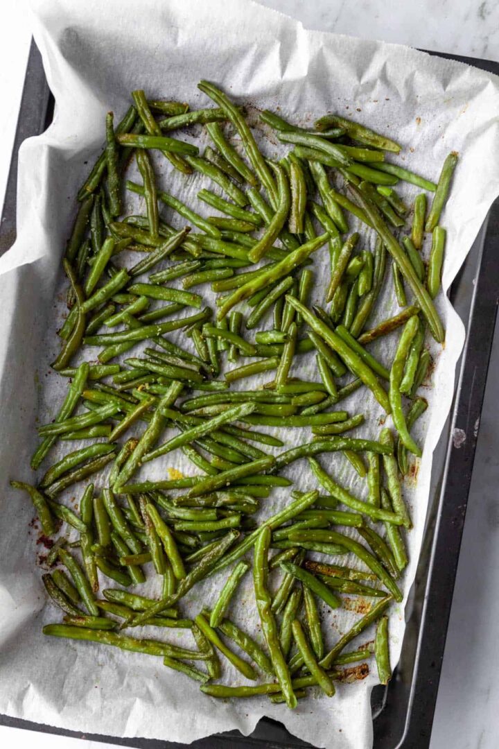 a large baking tray with roasted green beans