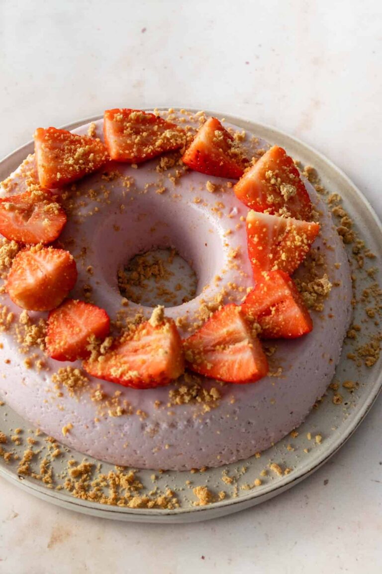 one large plate with a strawberry pudding cake with sliced strawberries on top and garnished with soft cookie crumbs