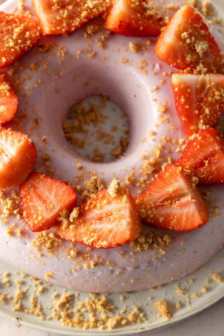 close up of a strawberry pudding cake with sliced strawberries and soft cookie crumbs