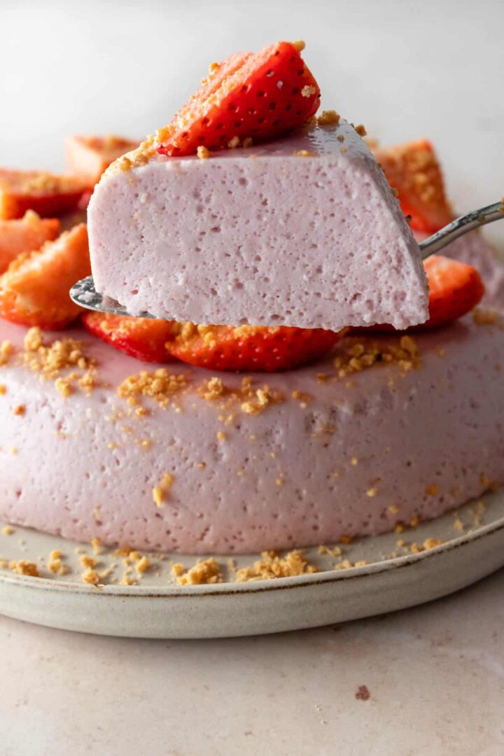 one slice of strawberry pudding cake with a slice of strawberry on top and the cake on the background