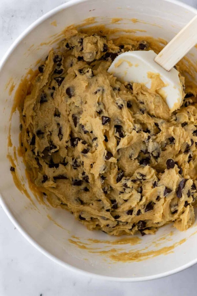 A bowl with cookie dough with chocolate chips and chocolate chunks