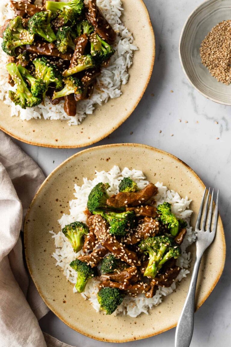 two plates served with white jasmine rice, broccoli florets, beef, and garnished with sesame seeds