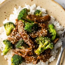 close-up to a plate served with broccoli, beef, white rice, and sesame seeds