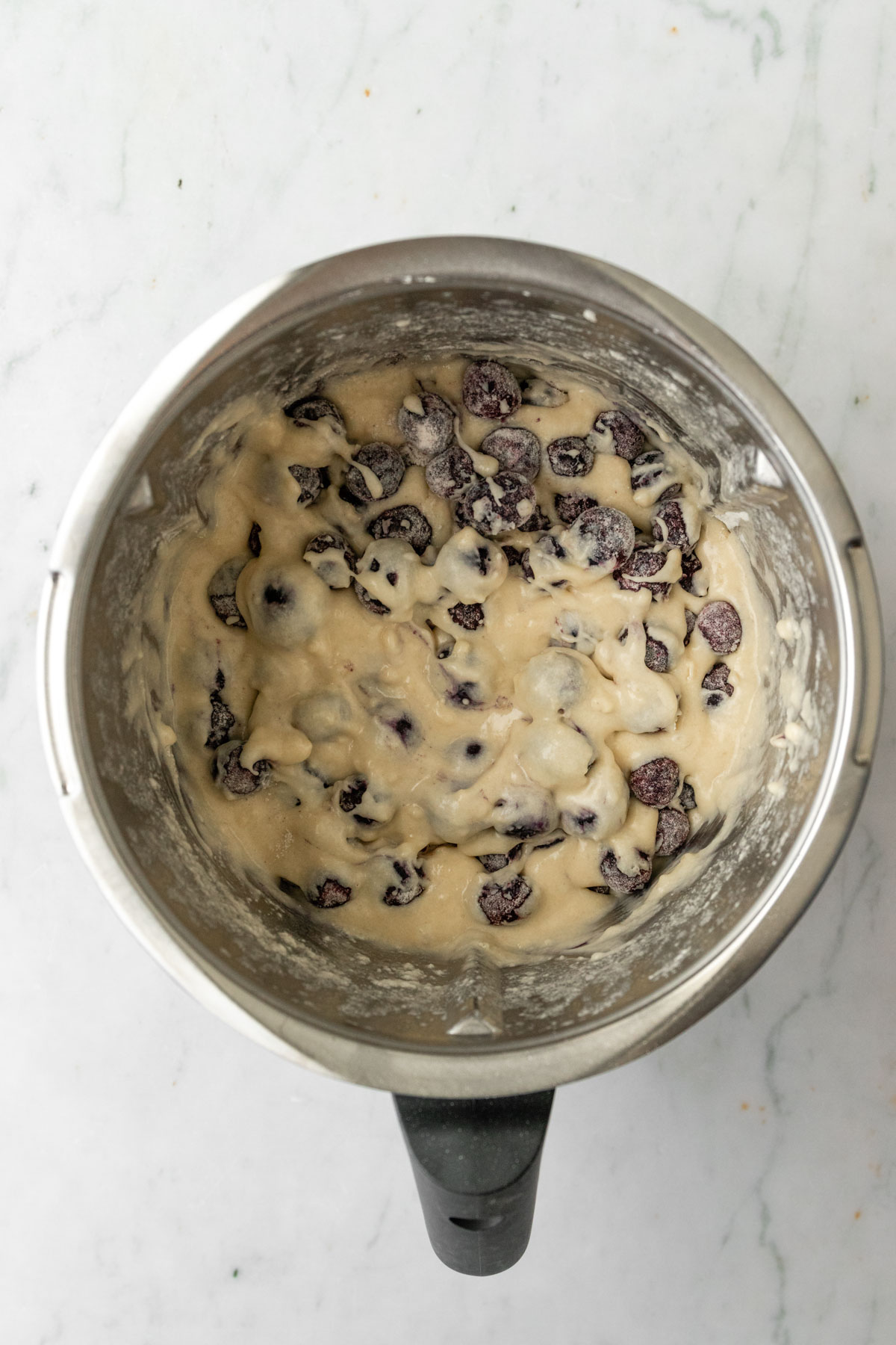 a Thermomix mixing bowl with muffin batter with blueberries inside