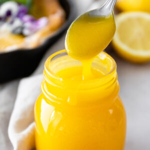 a glass jar with lemon curd and a spoon with lemon curd